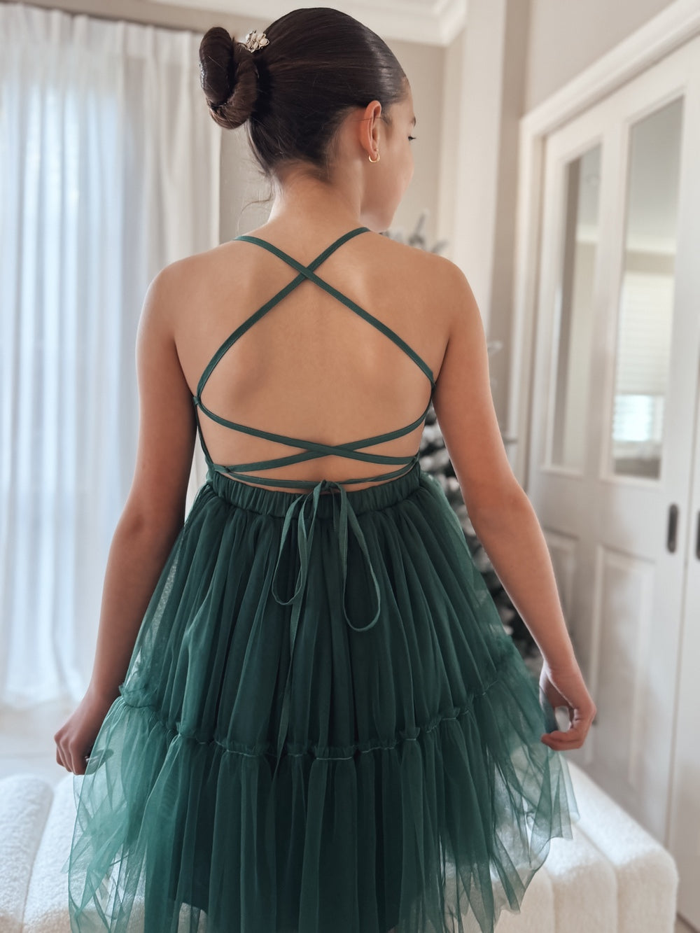Girl twirling in green tulle dress with lace-up back design