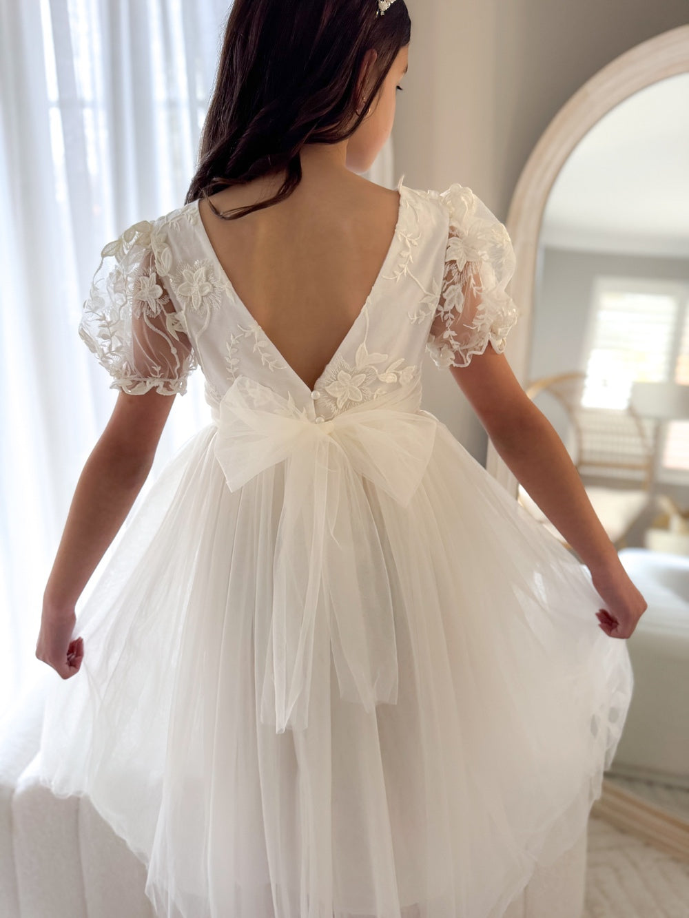 Back view showing V-shaped back and delicate pearl button detail on ivory dress