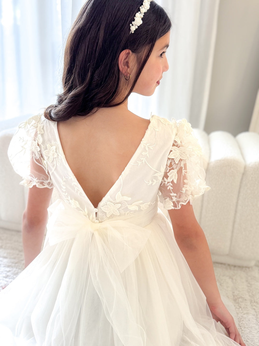Back view showing V-shaped back and delicate pearl button detail on ivory dress