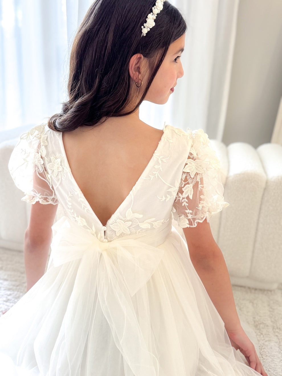 Back view showing V-shaped back and delicate pearl button detail on ivory dress