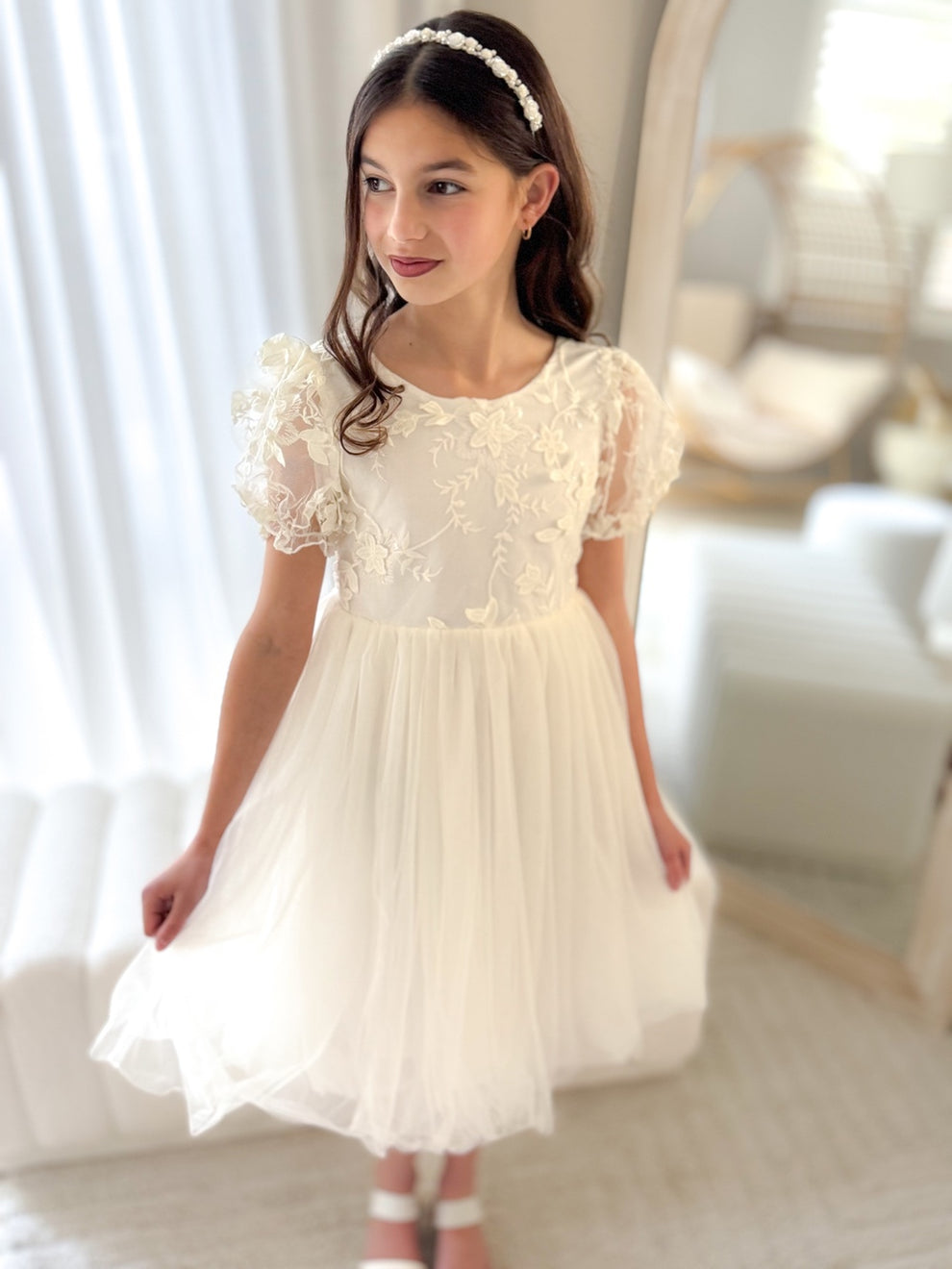 Detail of floral embroidery on sleeve and bodice of ivory girls dress