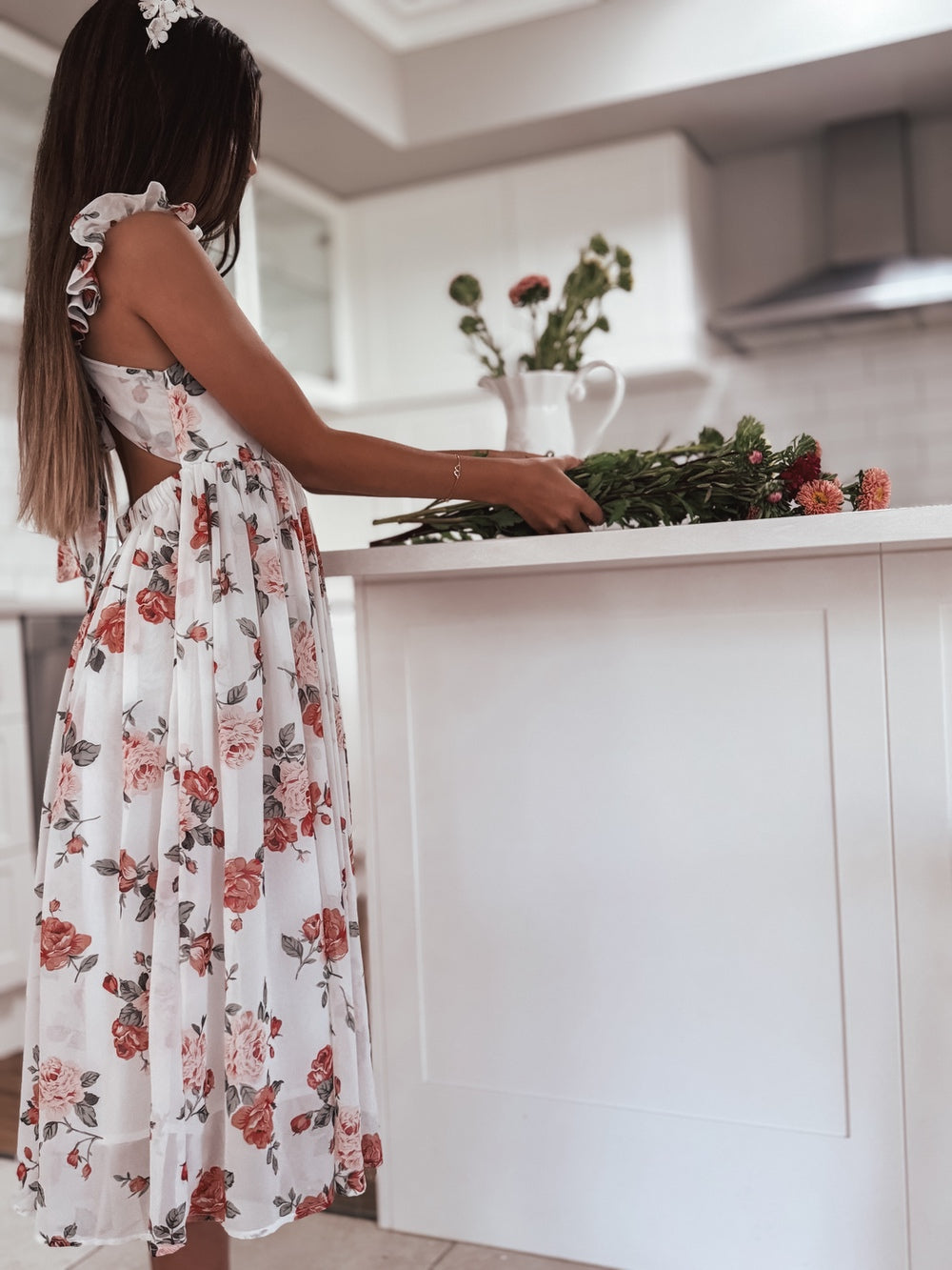 Side view of girl moving flowers in Leilani red floral party dress
