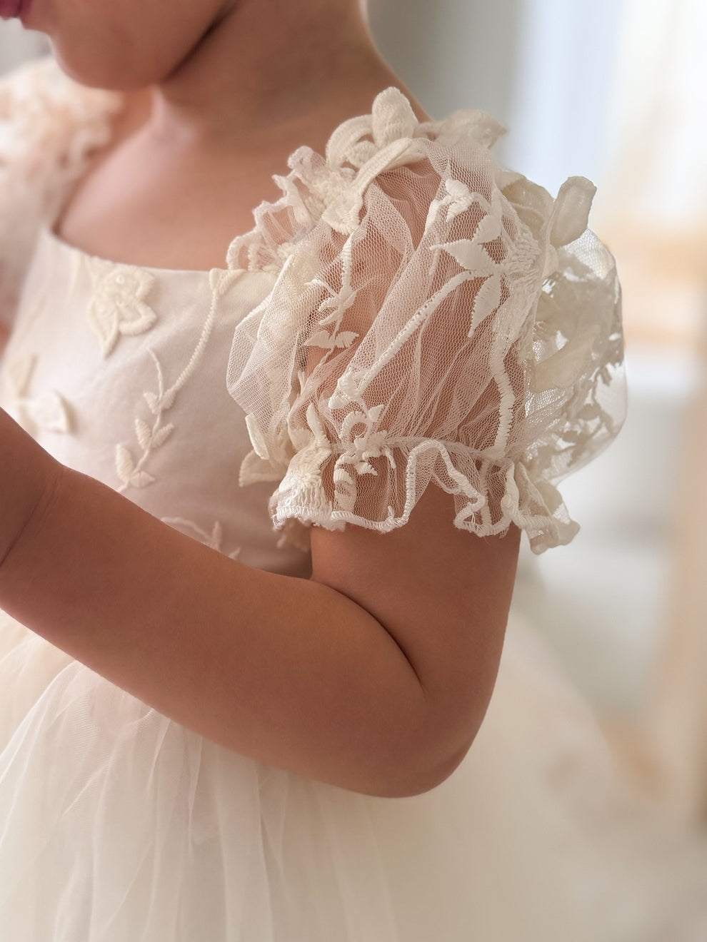 Side view of Lila Ivory Embroidered Baby Dress – puff sleeves and soft layered tulle