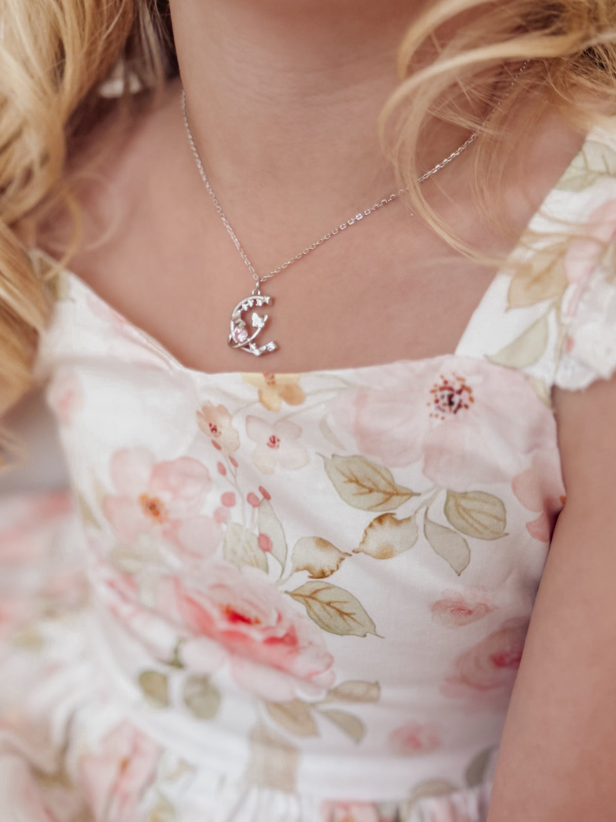 Close-up of silver girls necklace with sparkling crystal charm