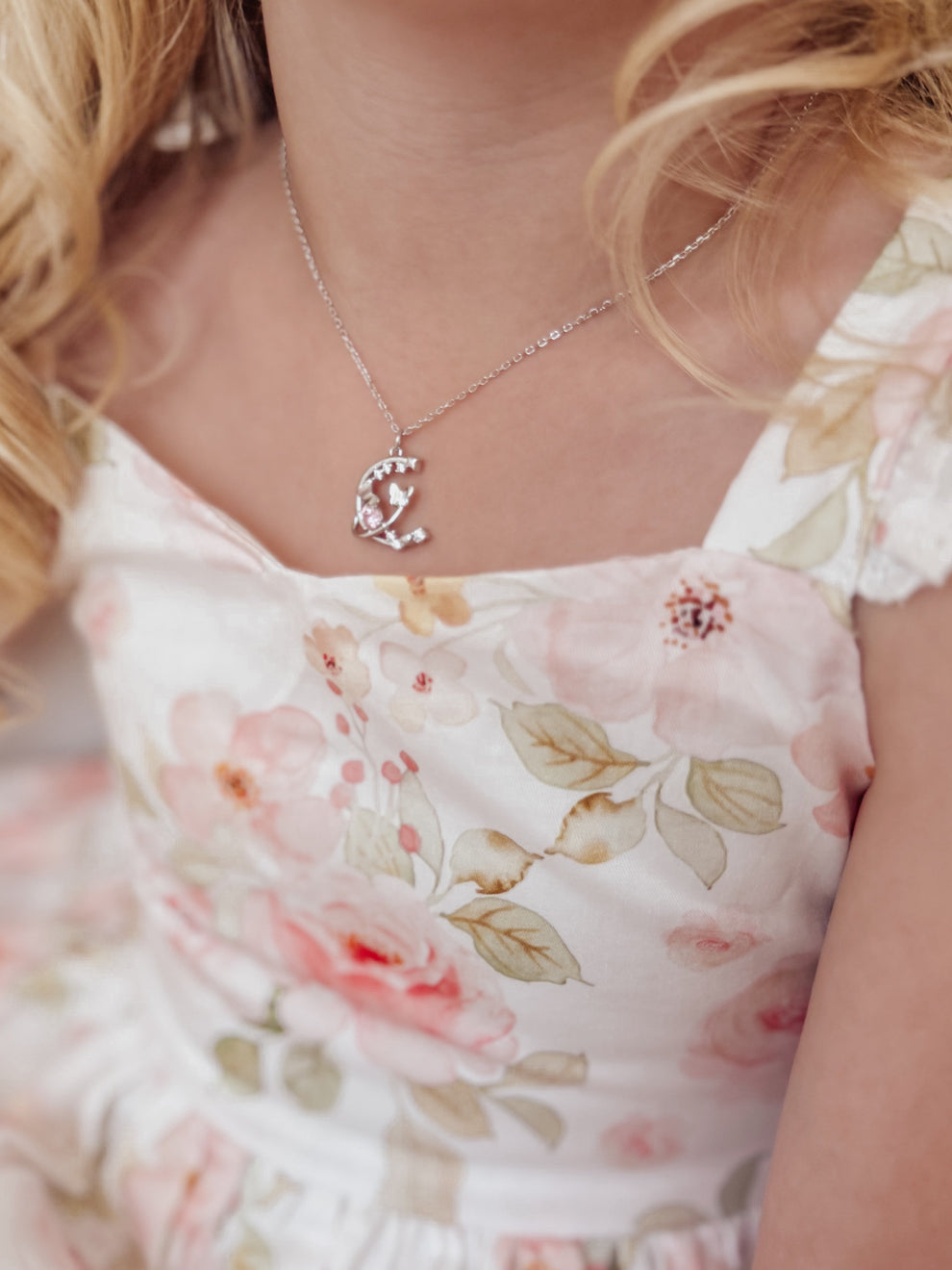Close-up of silver girls necklace with sparkling crystal charm