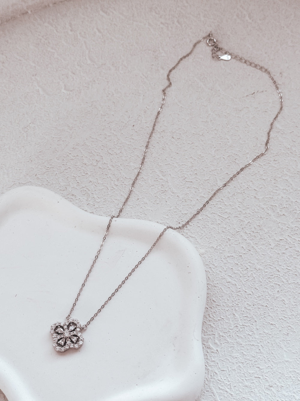 Necklace laid flat showing detailed clover and silver chain