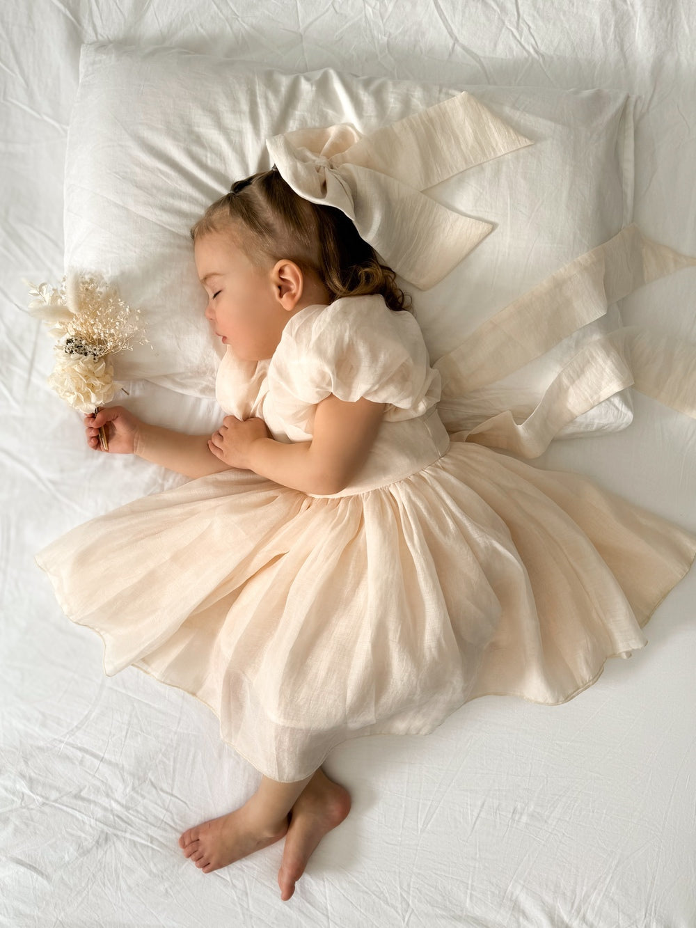 Baby wearing Lucy Champagne Dress with puff sleeves and bow on the back
