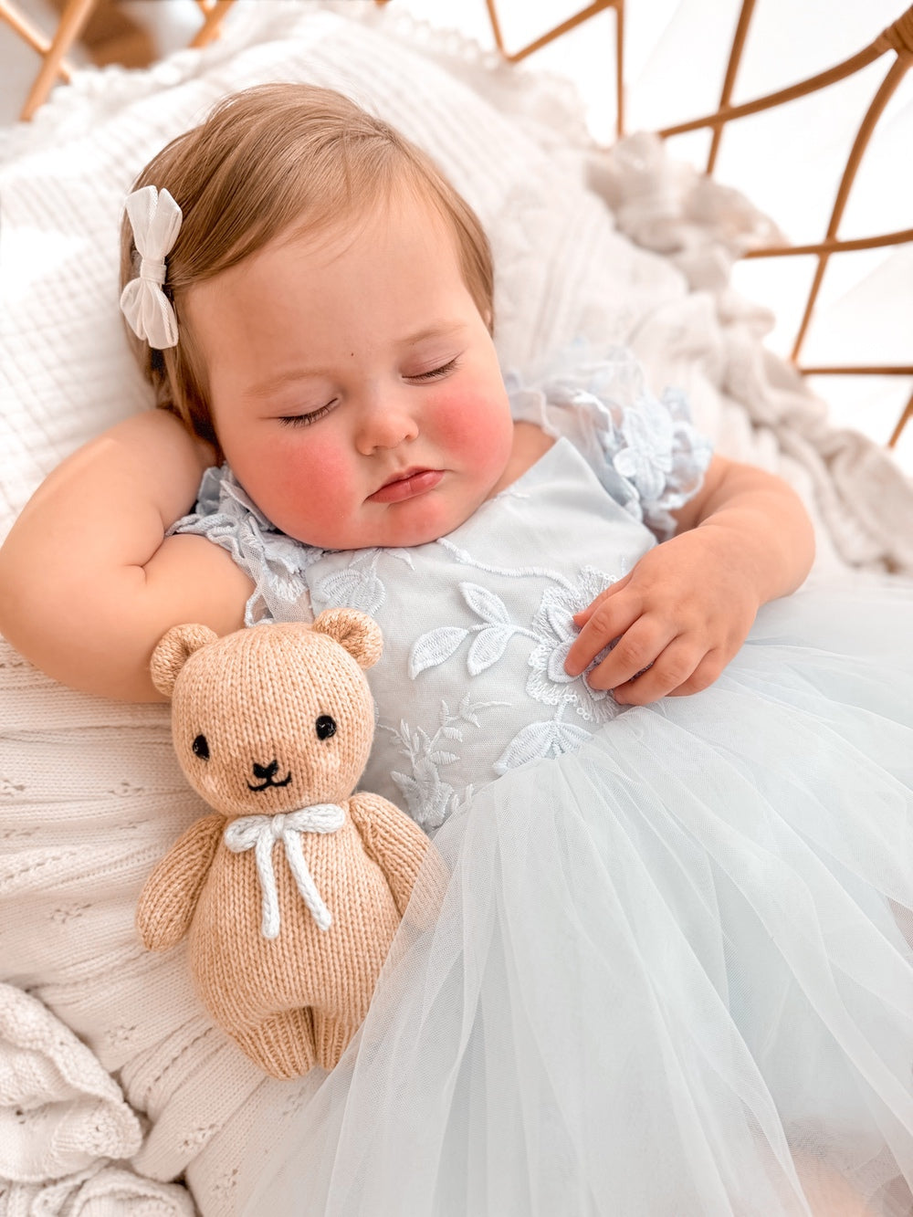 Lila dusty blue embroidered baby dress, reclining close-up.