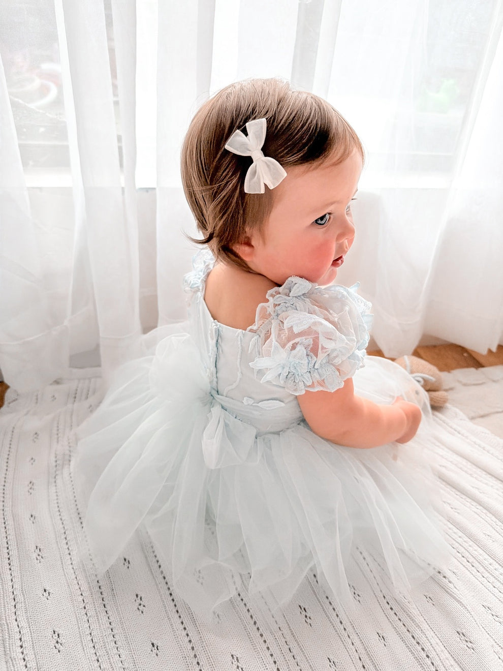 Lila dusty blue baby dress, three-quarter back view.