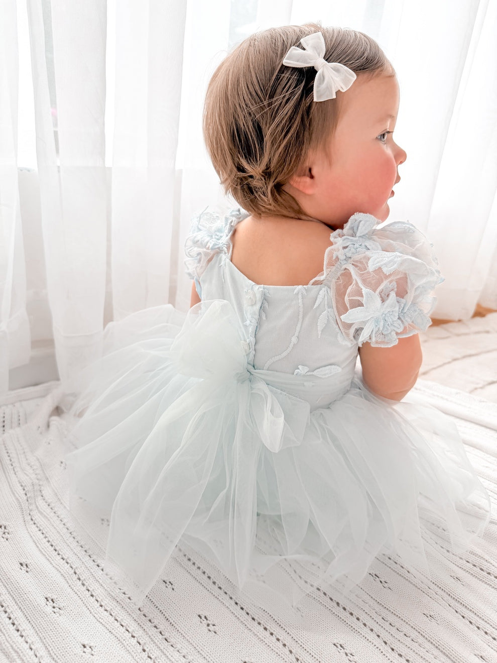 Lila dusty blue baby dress with button back and tulle bow.