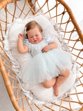 Lila dusty blue baby dress with puff sleeves, full view lying down.