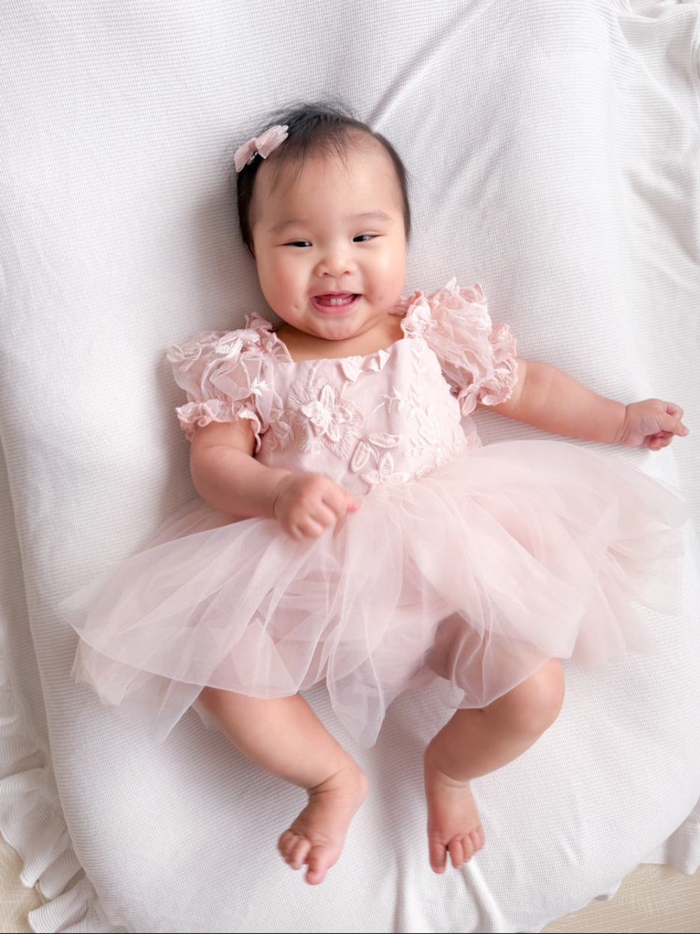 Lila soft pink embroidered baby dress worn lying down.
