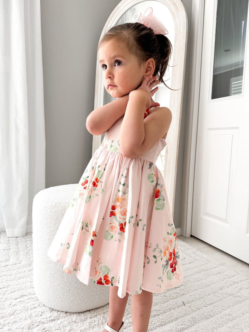 Girl wearing the Marley Girls Christmas Dress with pink and red floral print, twirling indoors - a joyful floral girls’ Christmas dress.