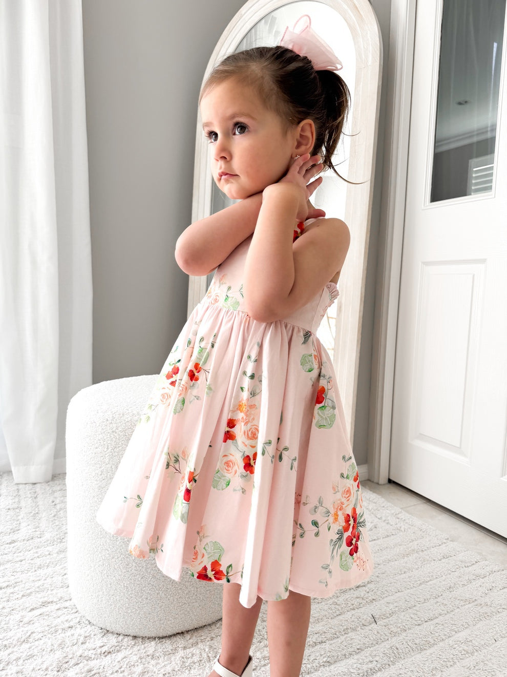 Girl wearing the Marley Girls Christmas Dress with pink and red floral print, twirling indoors - a joyful floral girls’ Christmas dress.