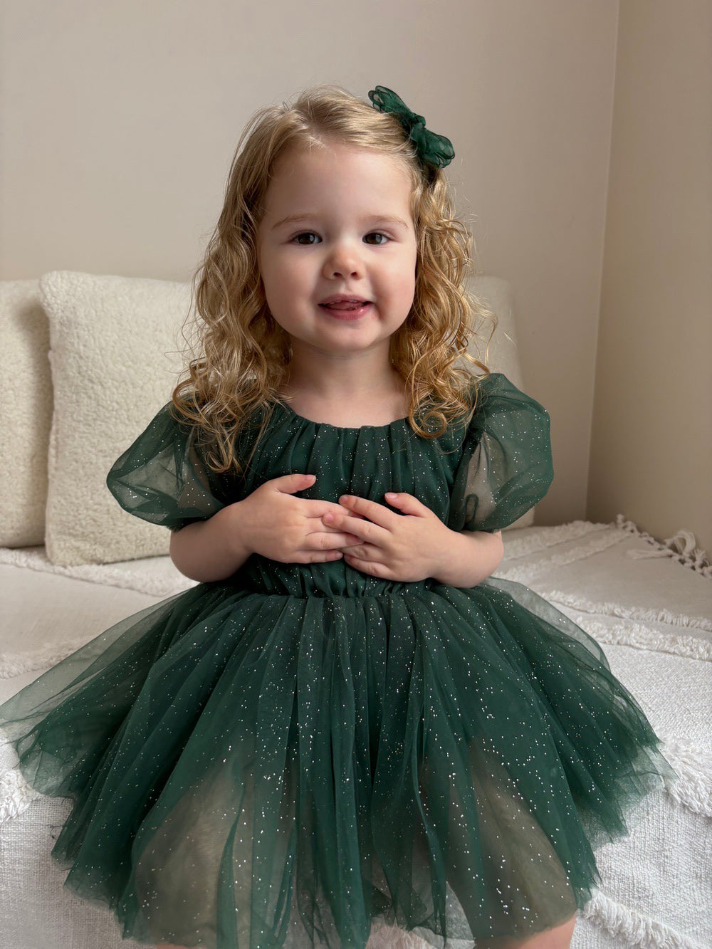 Girl’s festive romper in emerald green shimmer fabric with bow and short sleeves