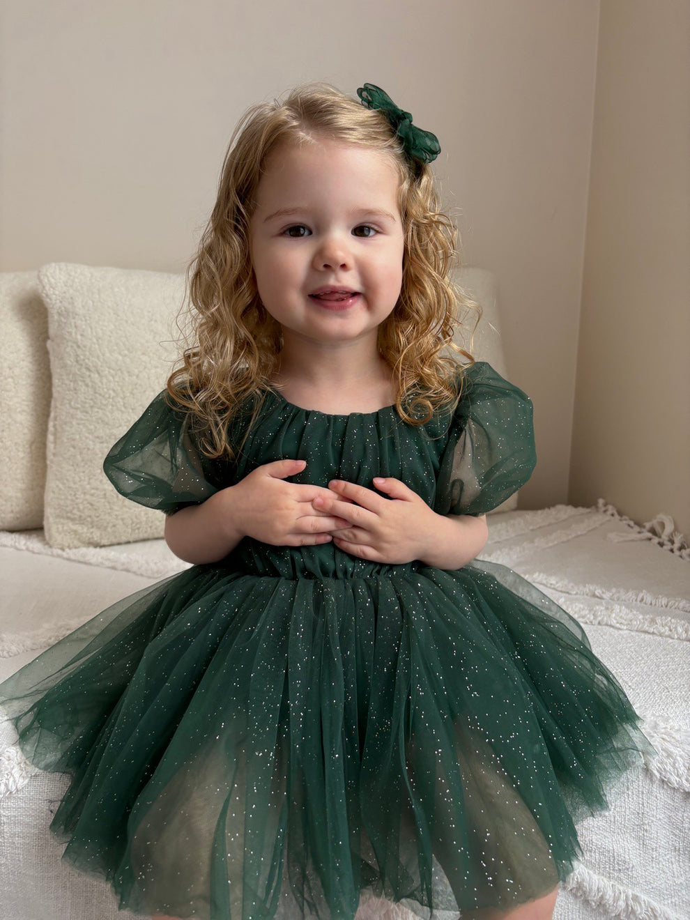 Girl’s festive romper in emerald green shimmer fabric with bow and short sleeves