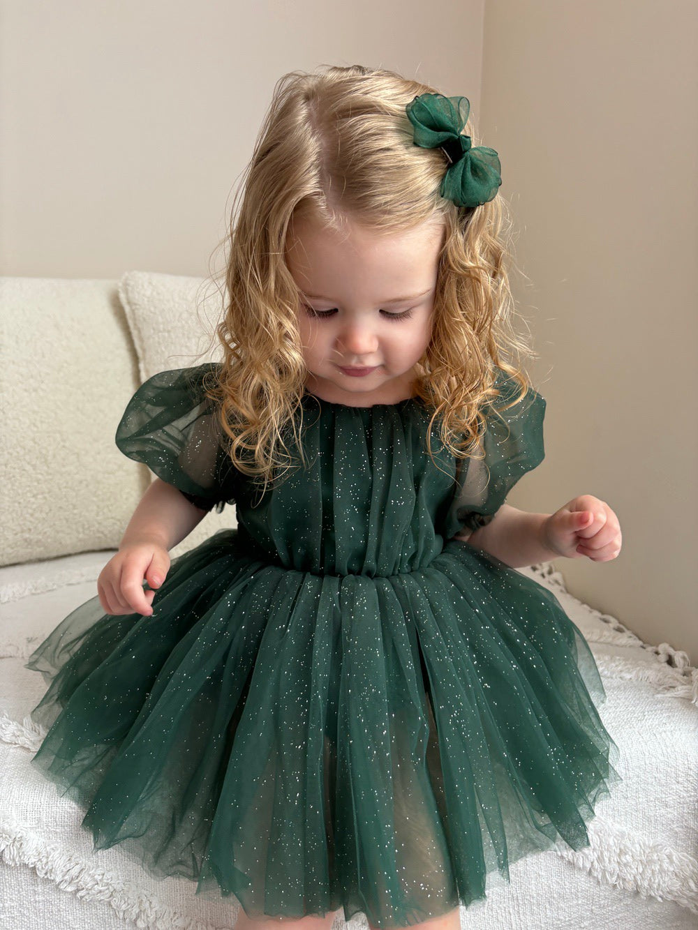 Baby girl wearing Nina Green Sparkle Christmas Romper with puff sleeves and bow back