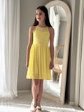 Tween girl in a yellow graduation dress standing in front of a mirror.