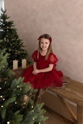 Girls red sparkly Christmas party dress modelled siting