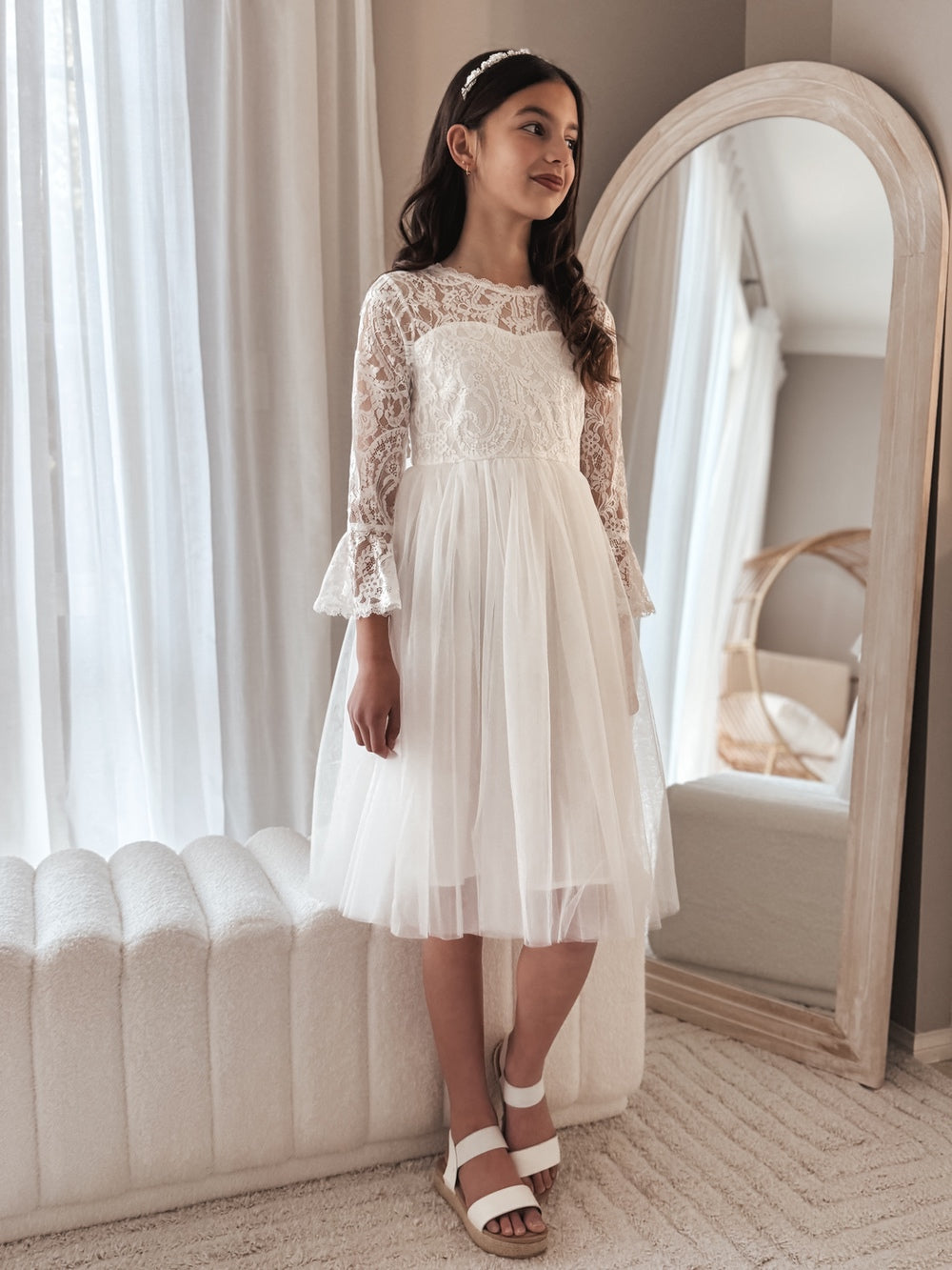 Girl wearing the Odette white flower girl dress, showing lace bodice and knee-length tulle skirt.