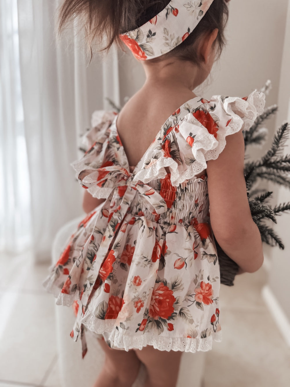 White cotton baby romper with festive rose design and frills