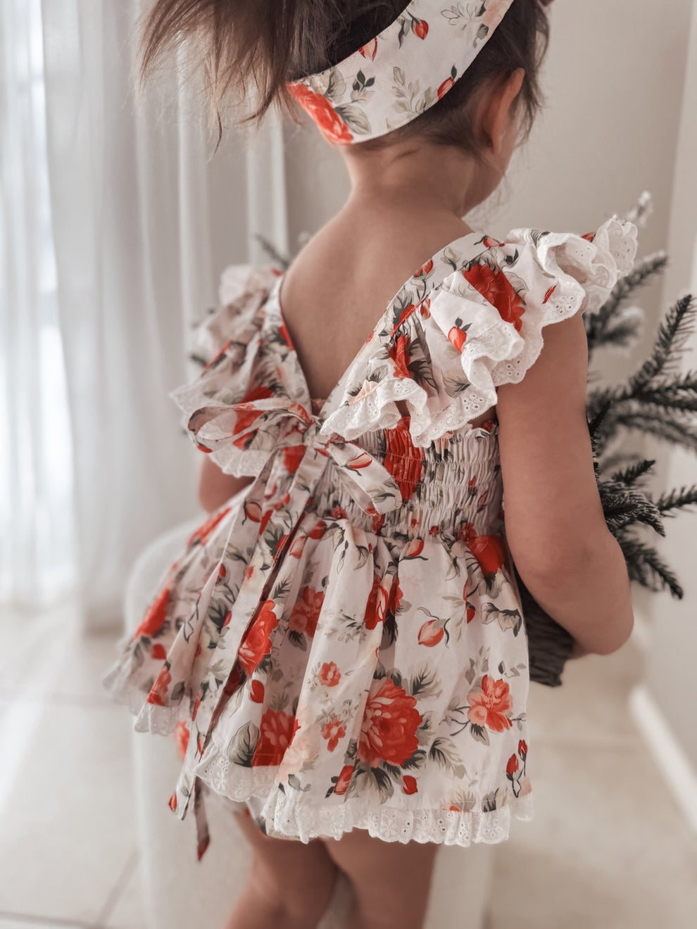 White cotton baby romper with festive rose design and frills