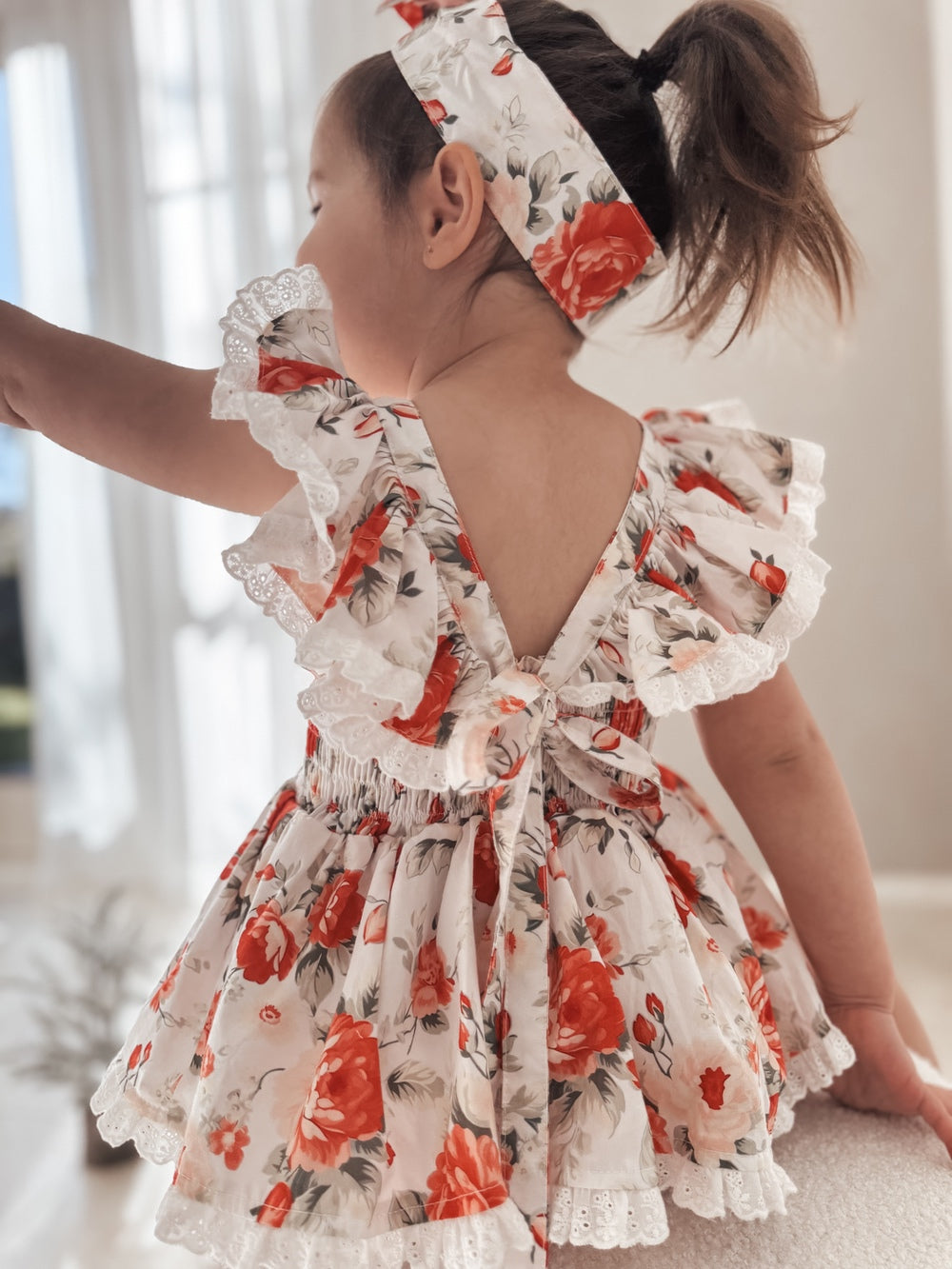 Baby romper showing floral rose print and ruffle back detail