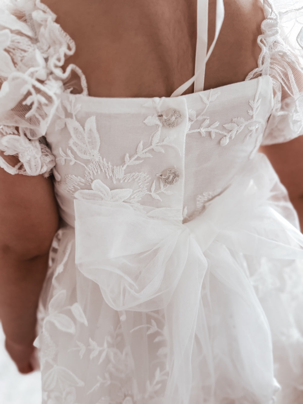 Back detail – tulle bow and three-button fastening on Petal White Baby Dress