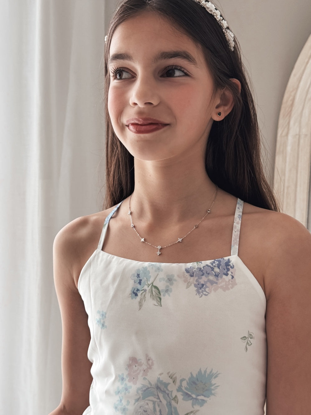Close-up of girls silver necklace with diamante circle and flower motif