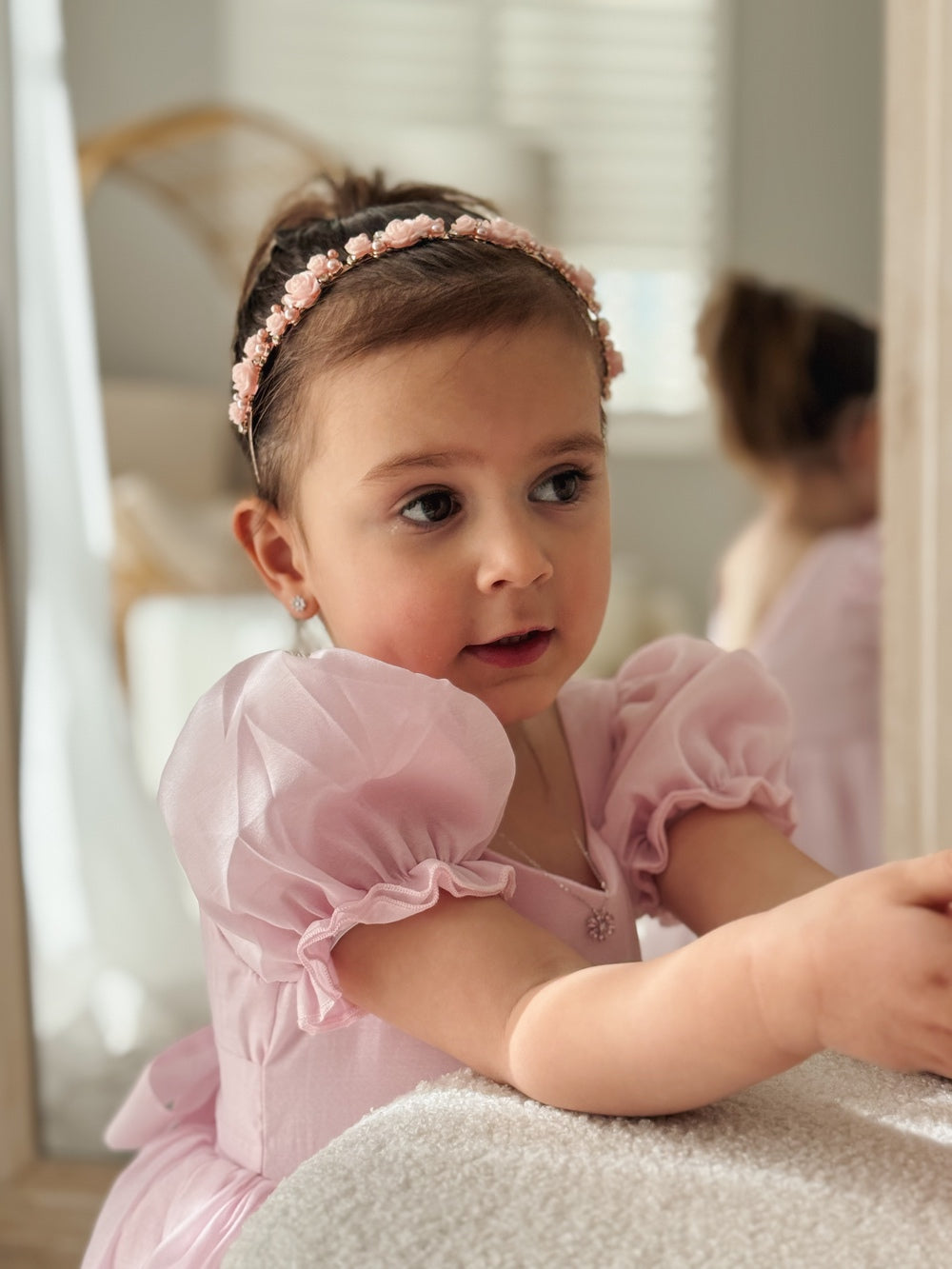 Girl wearing pink flower and pearl headband with curls