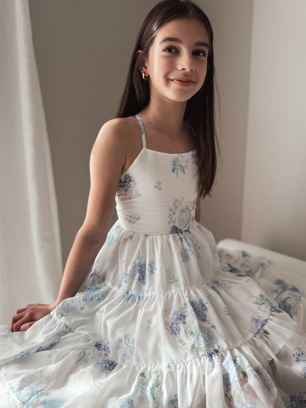 Tween girl sitting in Phoebe Blue Floral primary school graduation dress with skirt fanned out