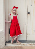 Girl modelling the Rosie red Christmas dress and matching head wrap in a doorway