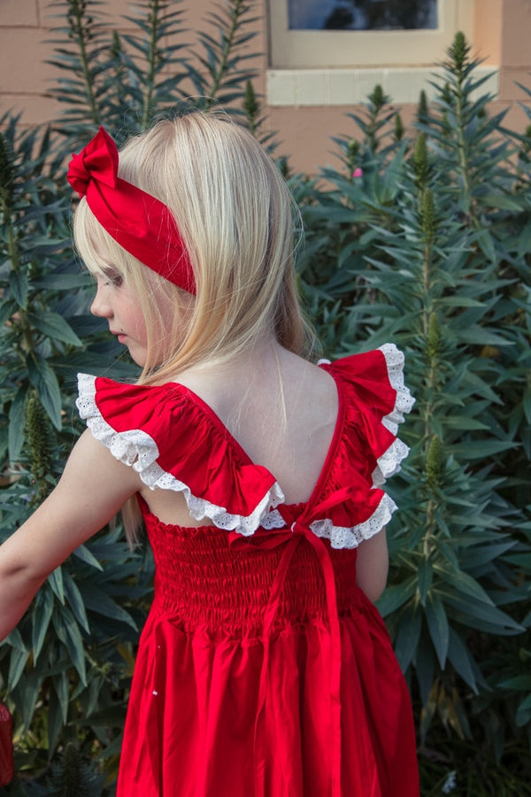 Close-up of the Rosie dress back showing white-edged ruffles, red ties and shirring
