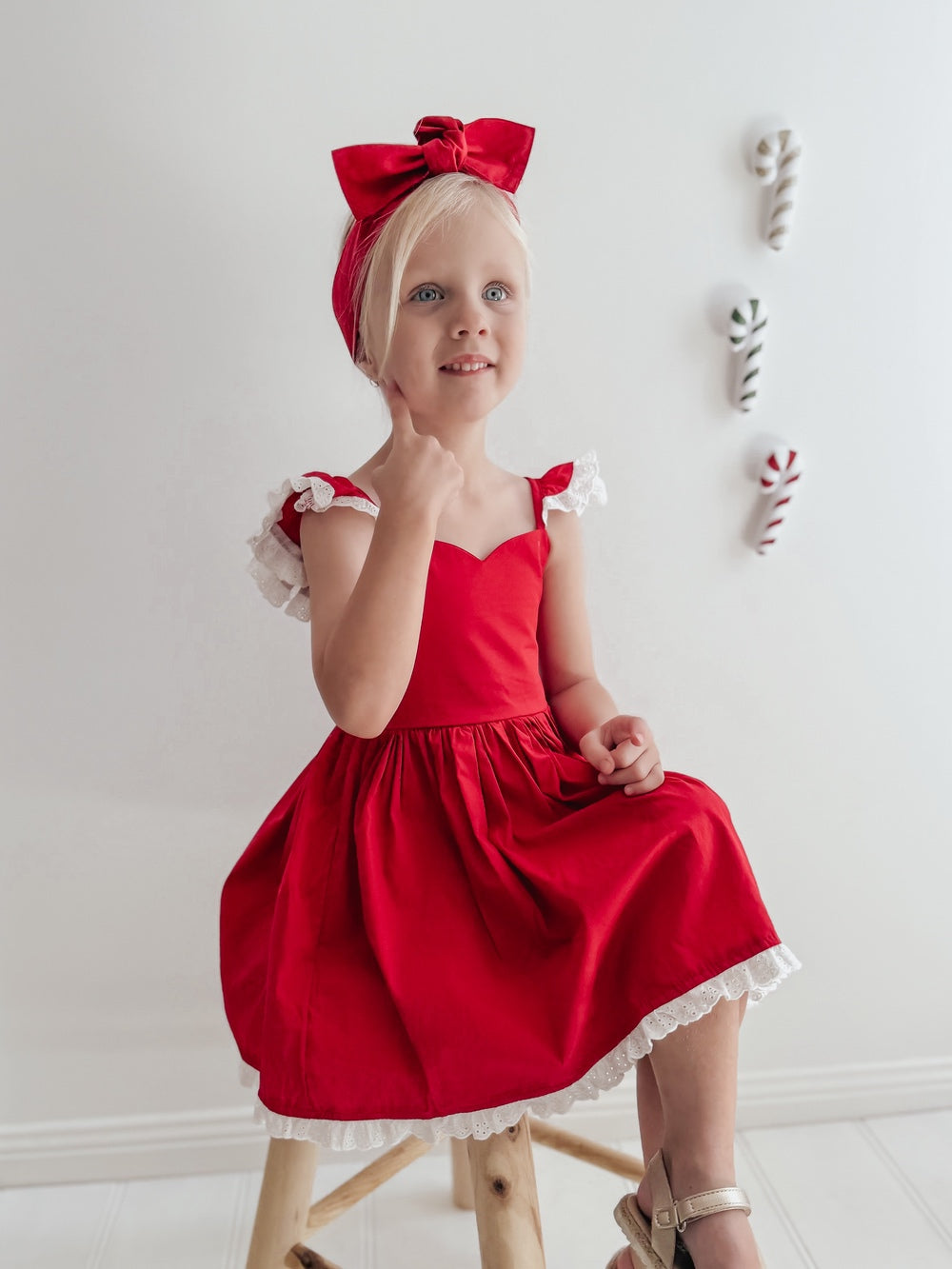Side view of a girl seated in the Rosie red Christmas dress, showing the white broderie hem