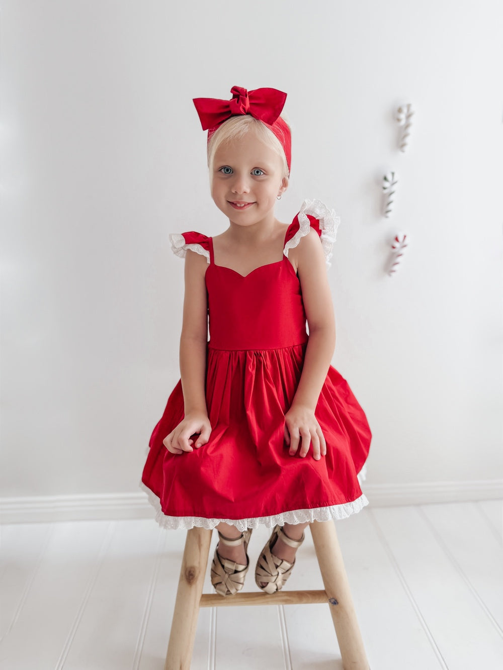 Front view of a girl seated in the Rosie red Christmas dress, showing the sweetheart neckline and gathered skirt