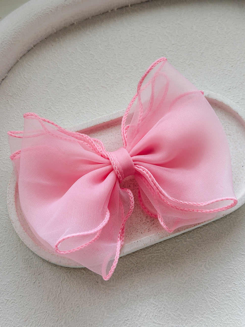Close-up of pink wavy hair bow on white background