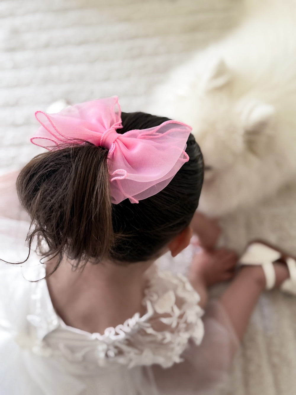 Girl wearing wavy pink bow clip with curly hair
