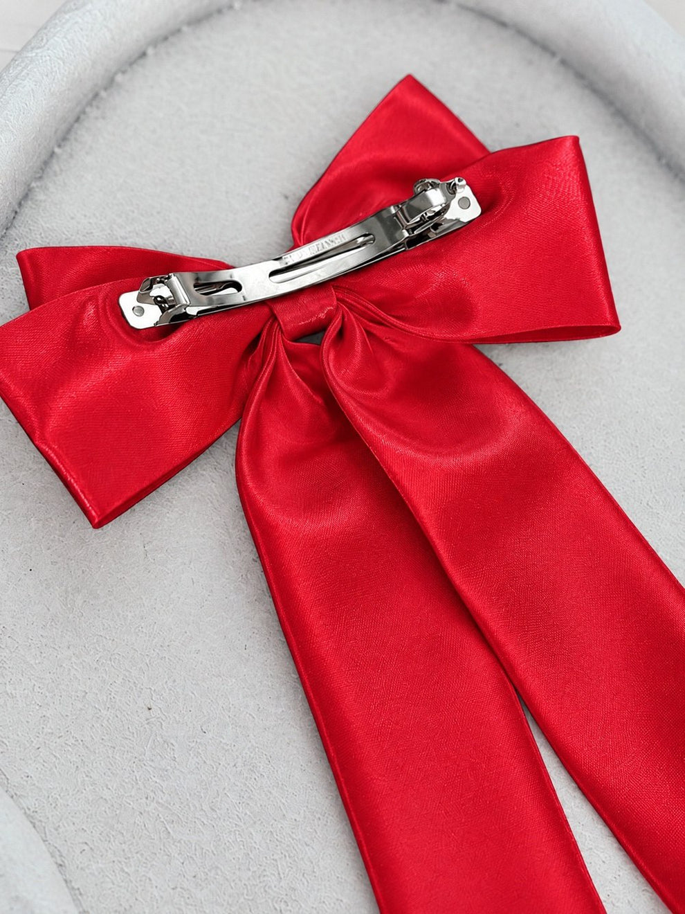 Back of the Amelie red satin hair bow showing the metal barrette fastening.