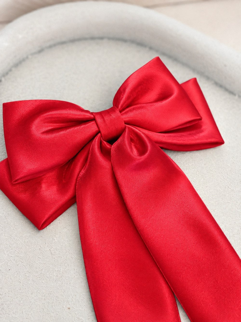Close-up of the Amelie red satin bow showing the layered loops and centre knot.