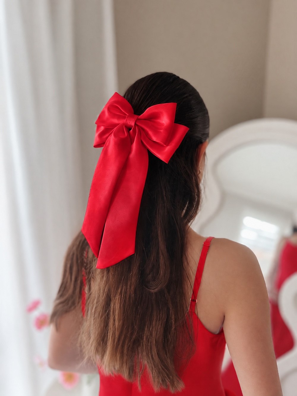 Side view of the Amelie red satin hair bow worn with a red dress.