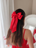 Side view of the Amelie red satin hair bow worn with a red dress.