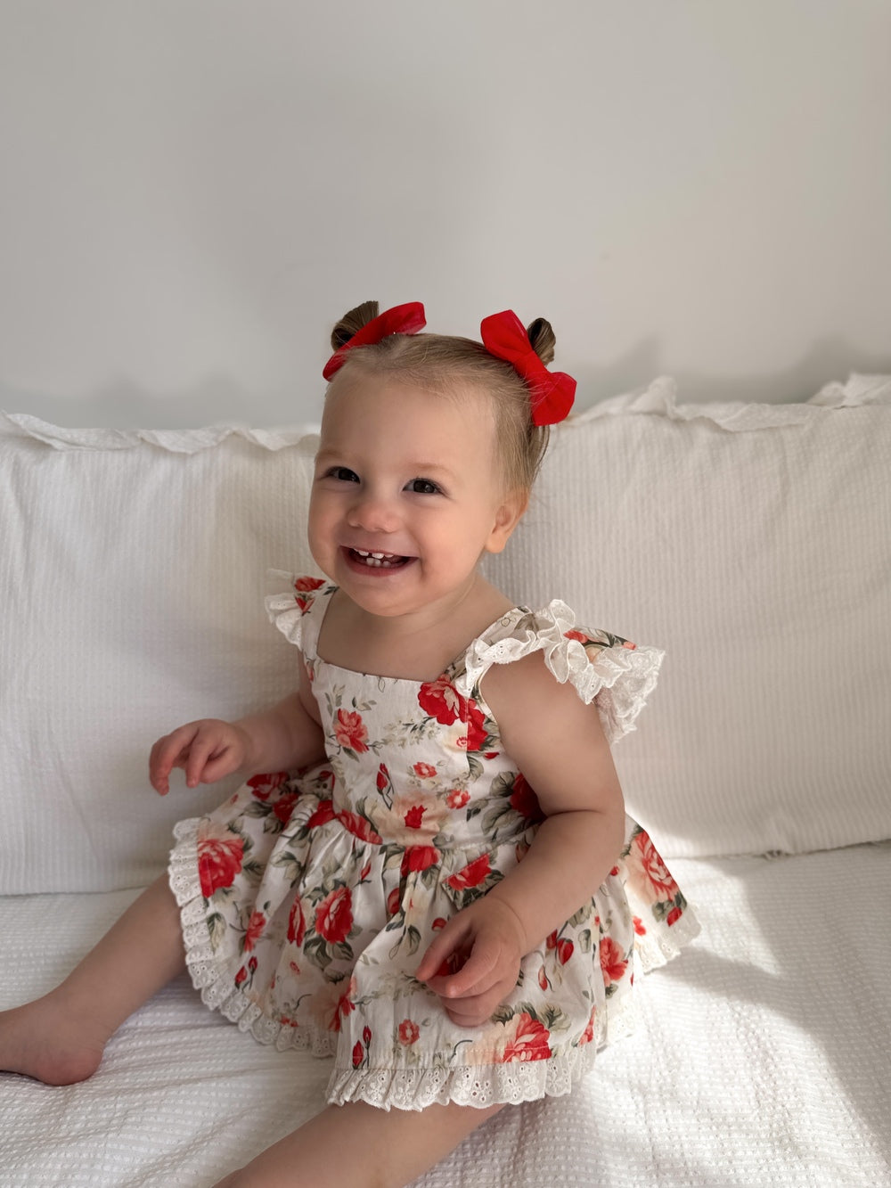 Close-up of Olive Baby Girls Christmas Romper showing floral print and broderie anglaise frills on straps