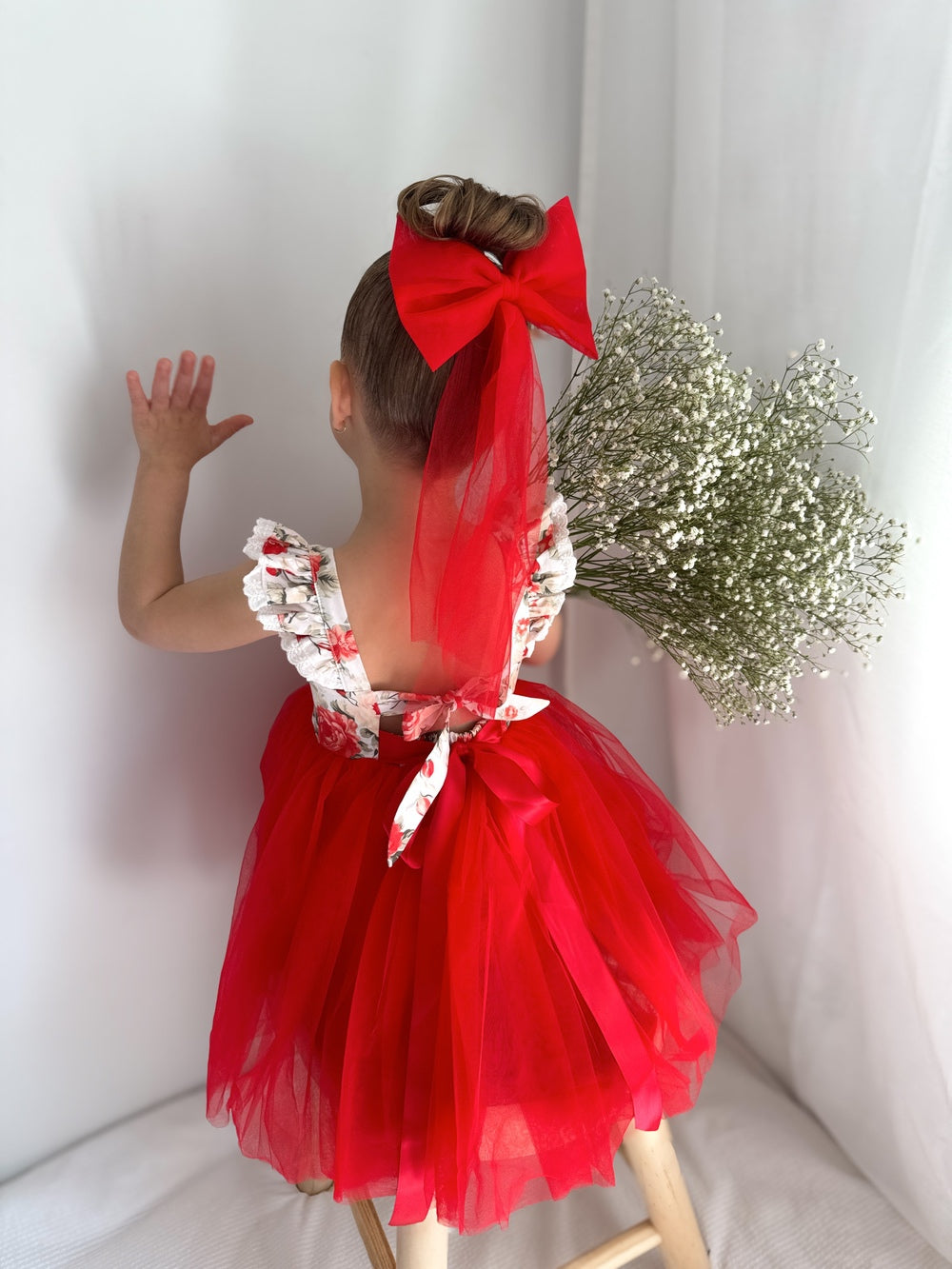 Girl wearing Stella Rose Girls Floral Christmas Dress with red floral print and tulle skirt