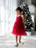 Girl wearing the Juniper red Christmas dress in a side view, showing the fitted bodice and tiered tulle skirt.