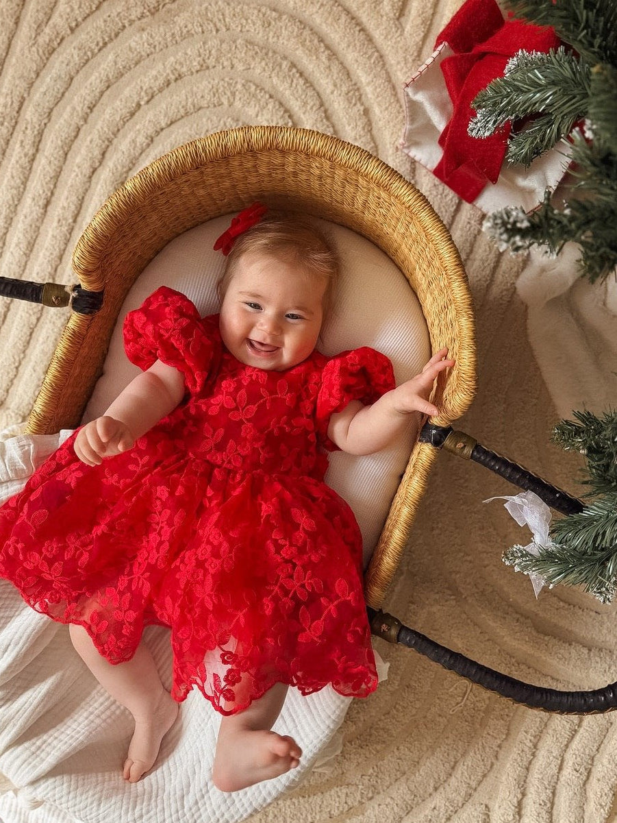 Baby wearing the Penelope red embroidered Christmas dress with puff sleeves and a full floral tulle skirt.