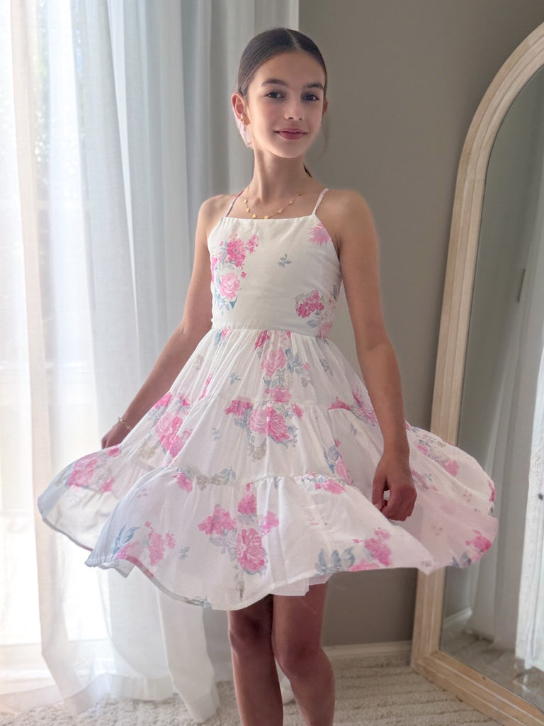 Tween girl twirling in pink flower print chiffon dress for garden party