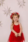 Girl wearing the Winterberry red flower crown with a red dress in front of paper stars