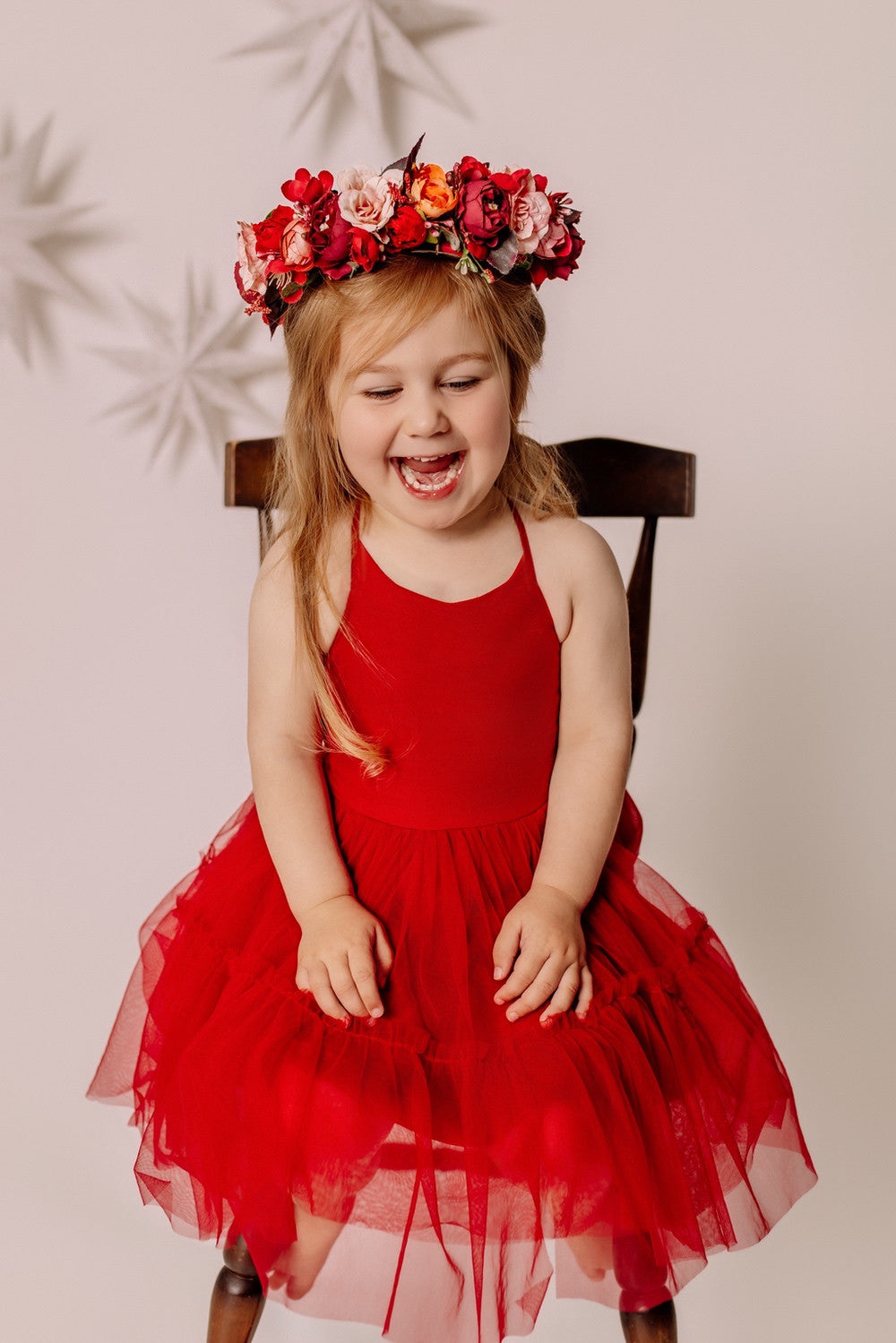 Girl seated on a wooden chair wearing the Winterberry Christmas flower crown