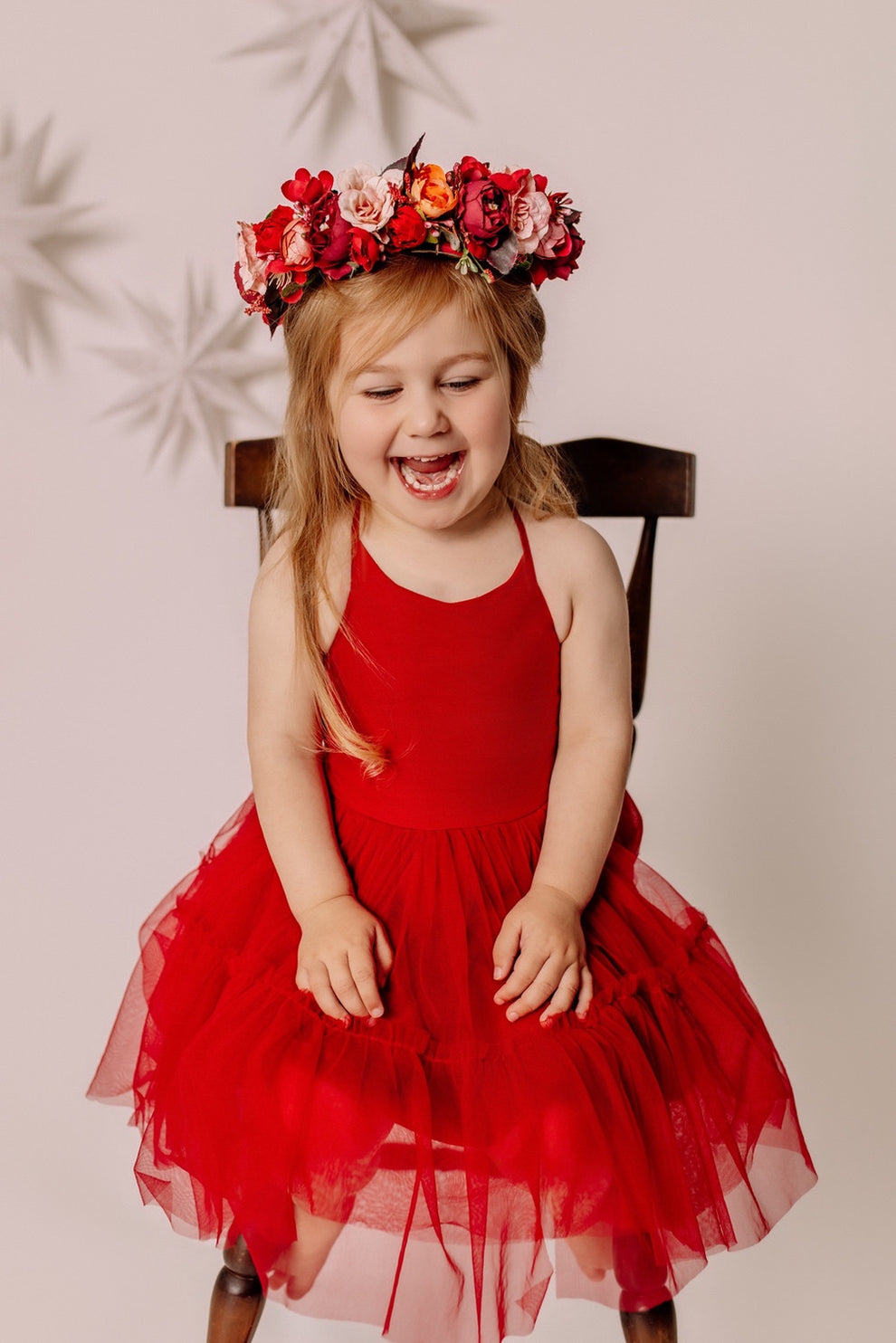 Girl seated on a wooden chair wearing the Winterberry Christmas flower crown