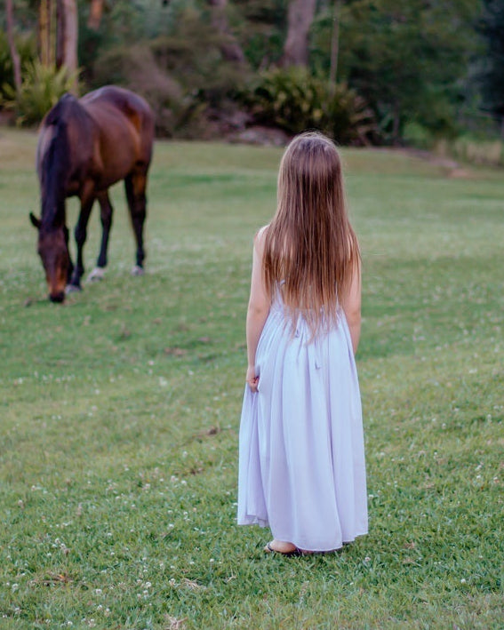 Flower girl in dusty blue Sofia Dress holding flowers at an outdoor wedding